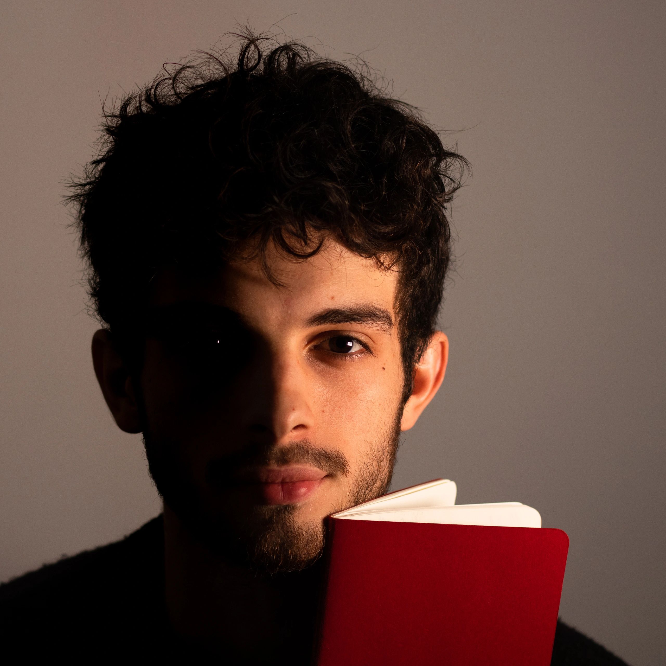 Portrait of a young man holding a red book