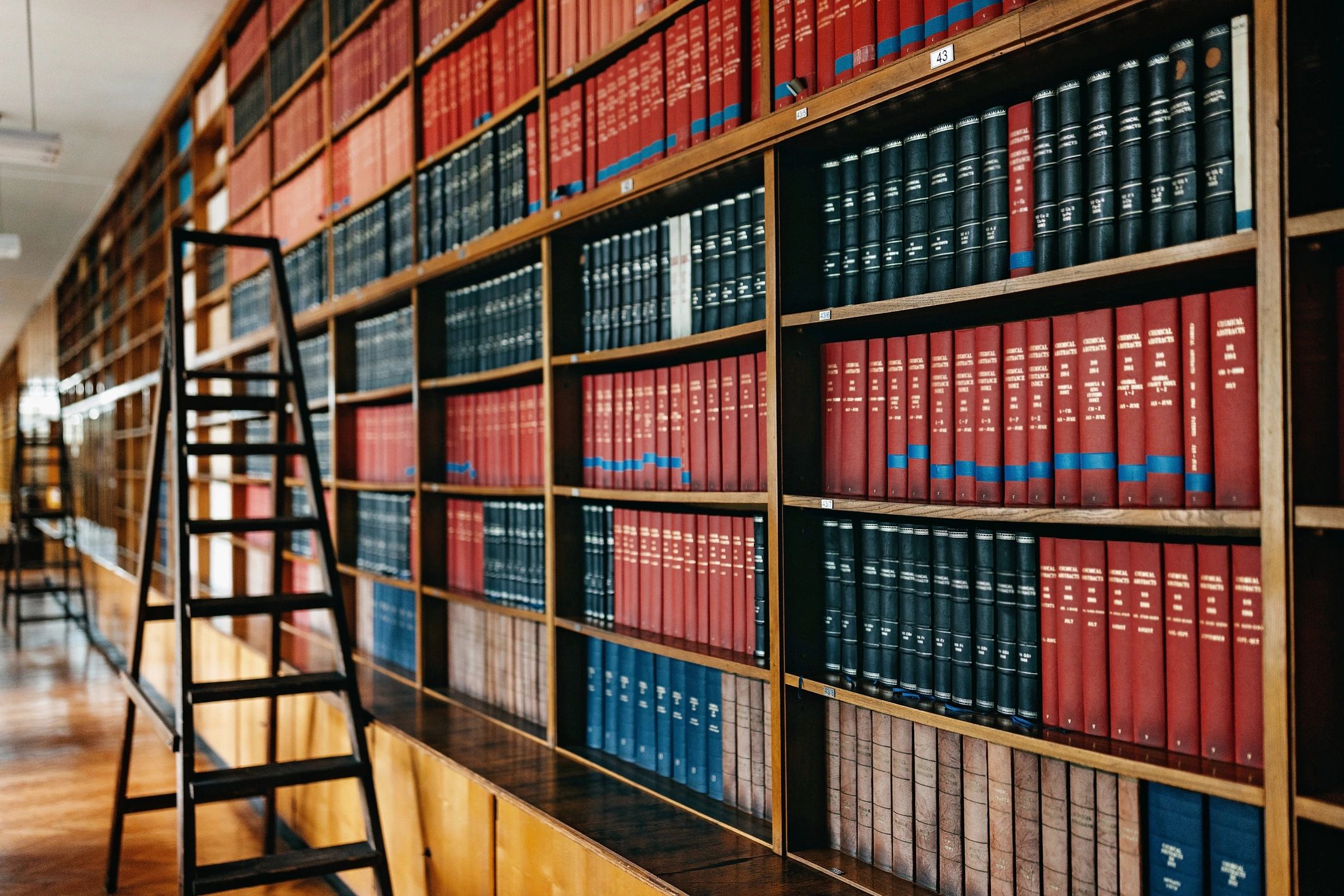 Library shelves with stacked hardcover books