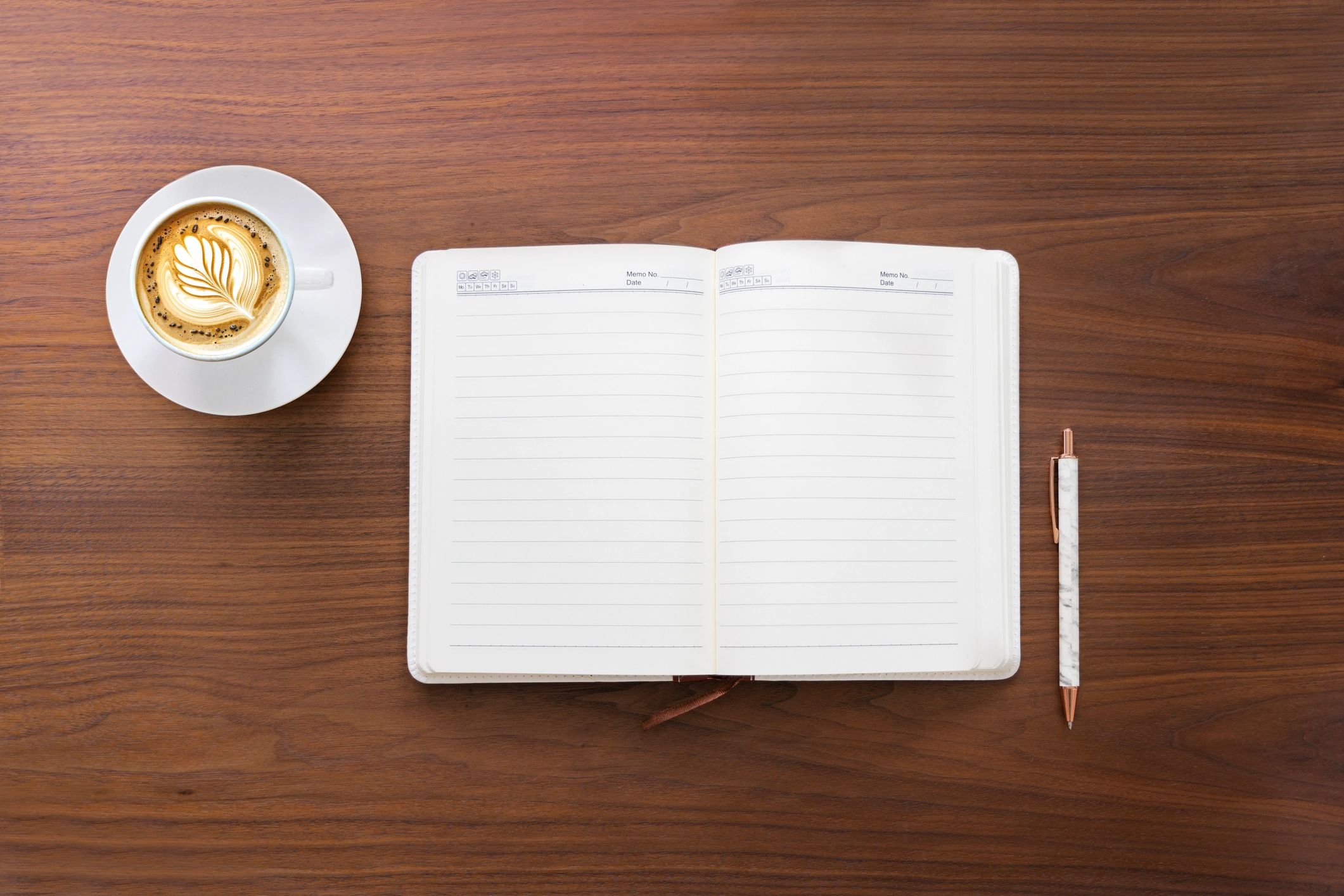 Open diary page and coffee cup on a wooden table