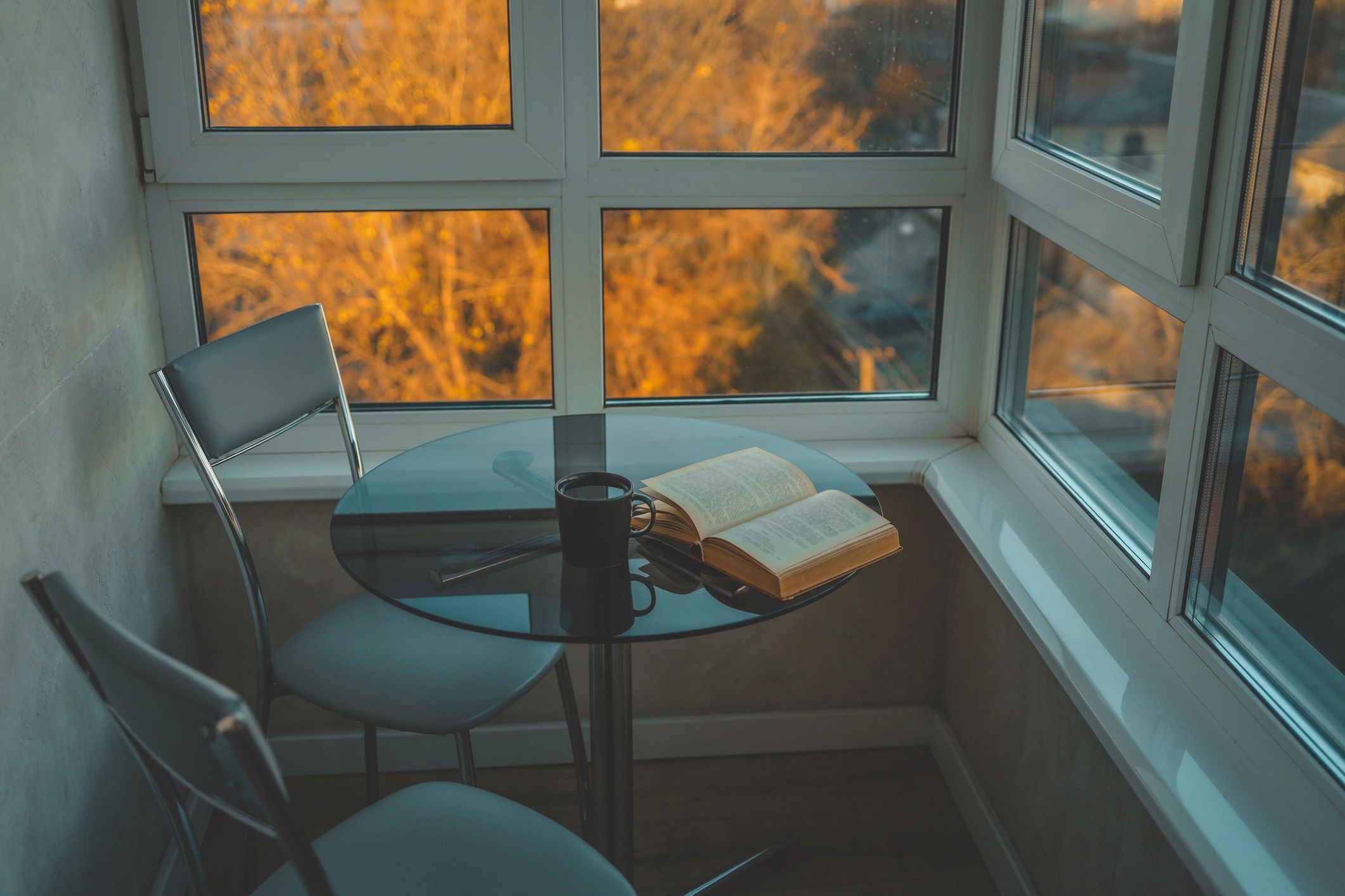 Cozy reading nook with an open book by a window at sunset